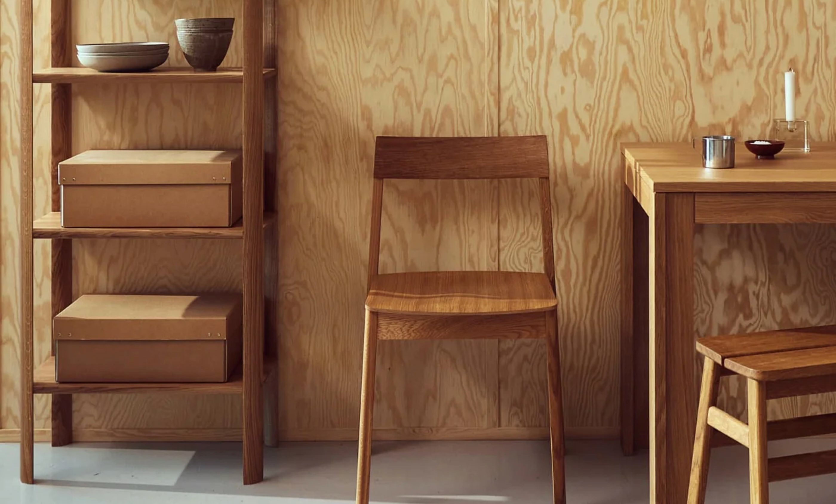 Minimalistisk spiseplass med trestol, eikebord og hylle i lyst treverk, dekorert med keramikk og oppbevaringsbokser i et nordisk interiør.