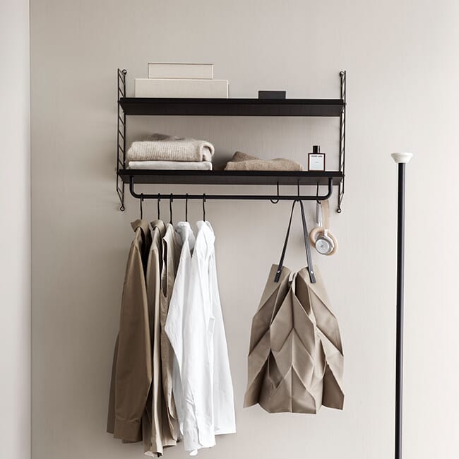 Sort String vegghengt klesstativ forfor oppbevaring brukt i gang med jakker og tilbehør.
