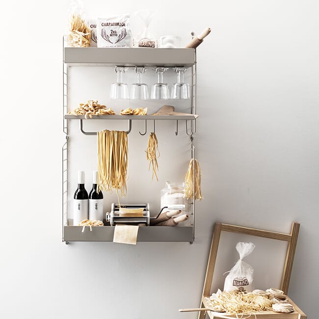 String vegghylle i kjøkkenet med hyller, kroker og oppbevaring. Vist med pasta, glass og kjøkkenutstyr for å vise fleksibel og praktisk kjøkkenløsning.