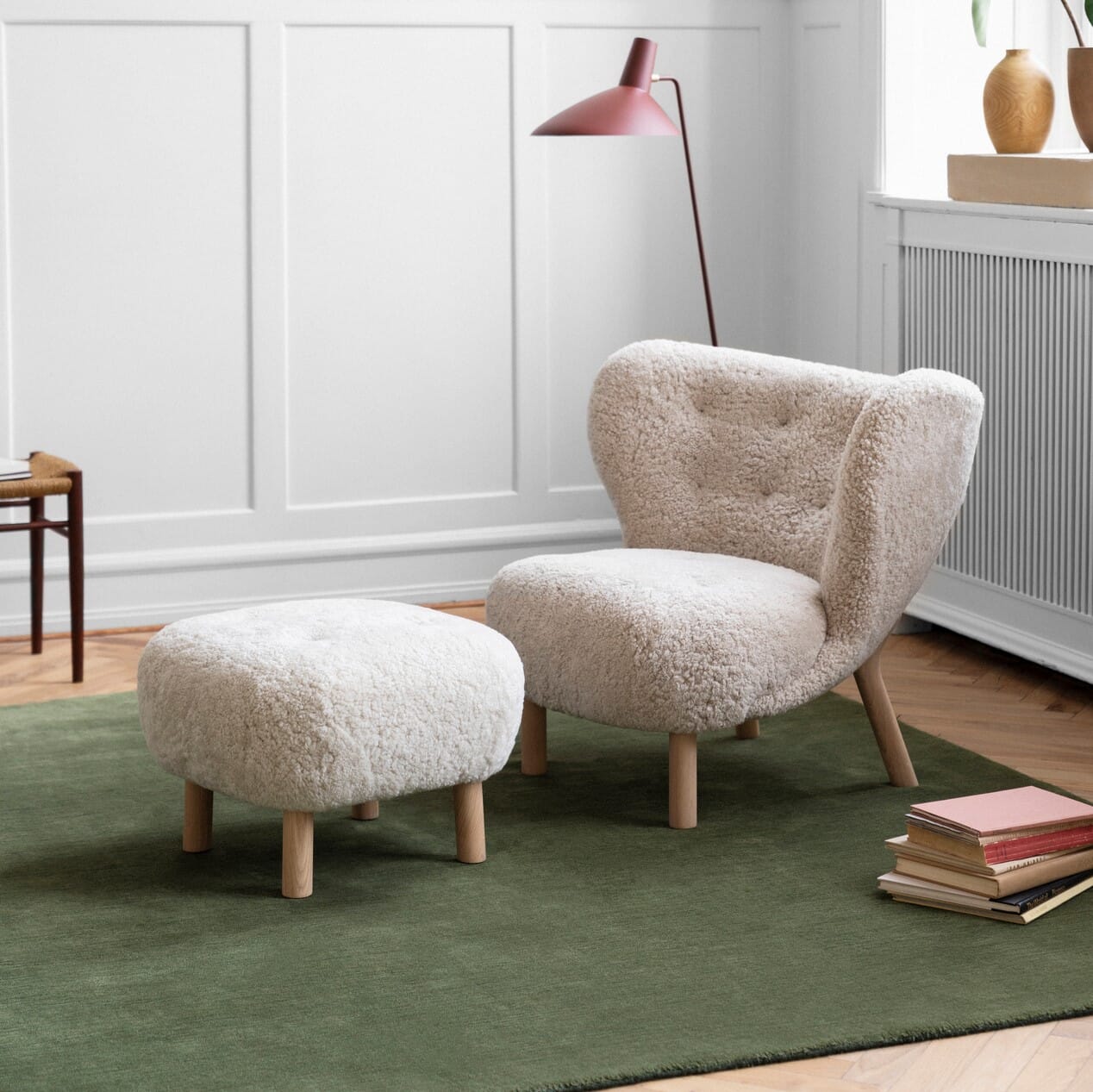 Lille Petra Lenestol med puff i fargen Moonlight og eik ben i klassisk stue på grønt teppe.