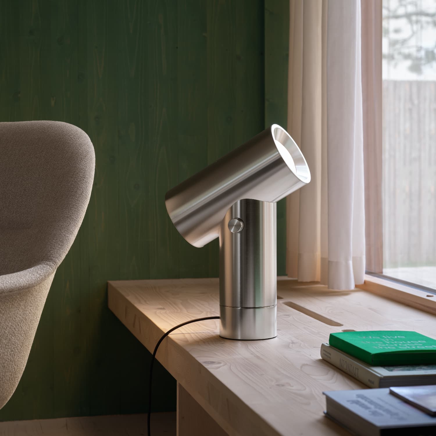 Beam bordlampe i polert aluminium plassert ved vindu