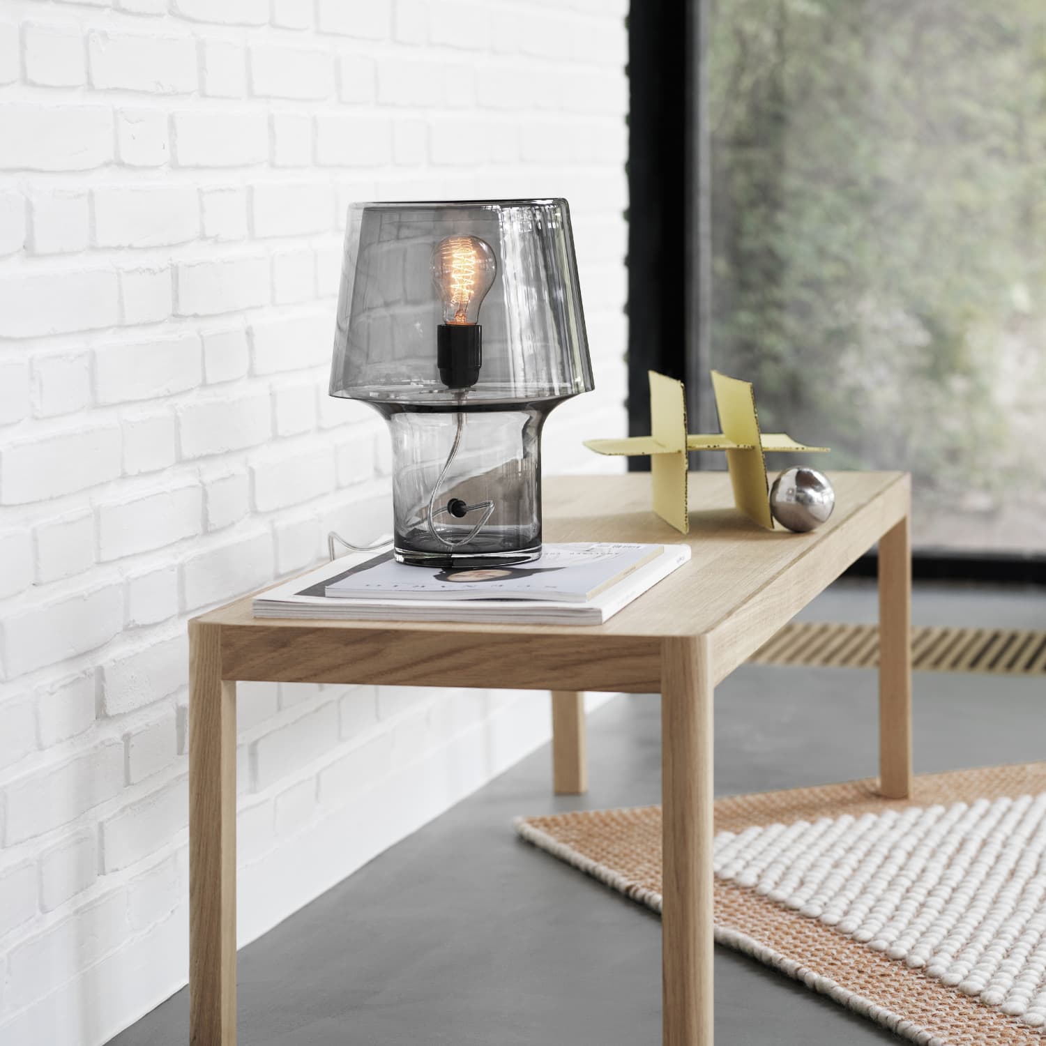 Cosy In Grey bordlampe fra Muuto plassert på trebord med myk stemningsbelysning