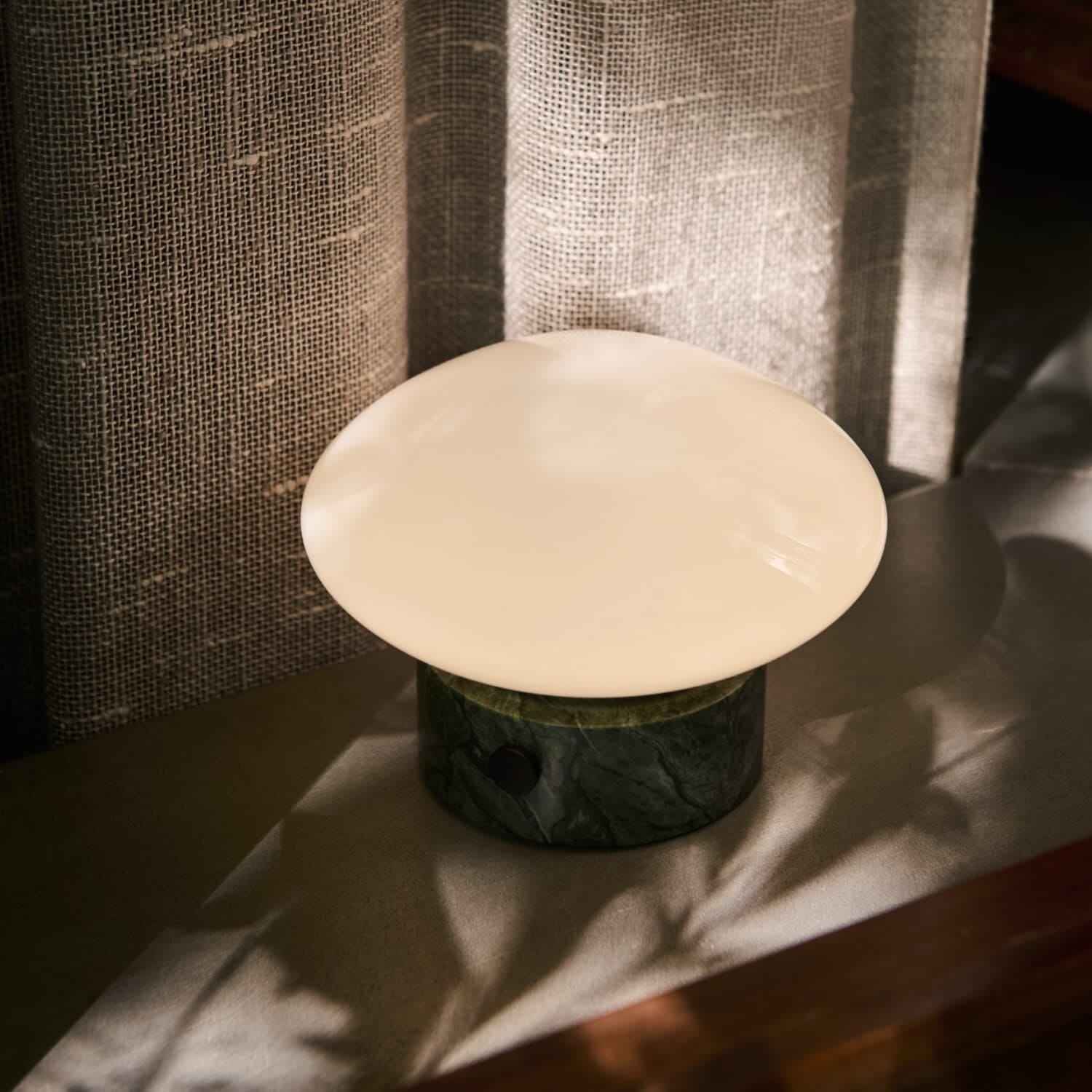 Oppladbar Mist bordlampe i glass og marmor verde plassert på en vinduskarm