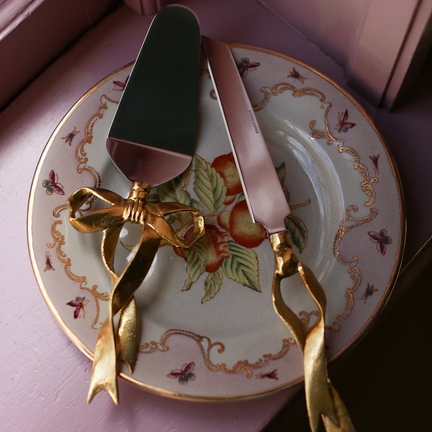 Kakespade og kakekniv med dekorativ sløyfe i resirkulert messing på en tallerken