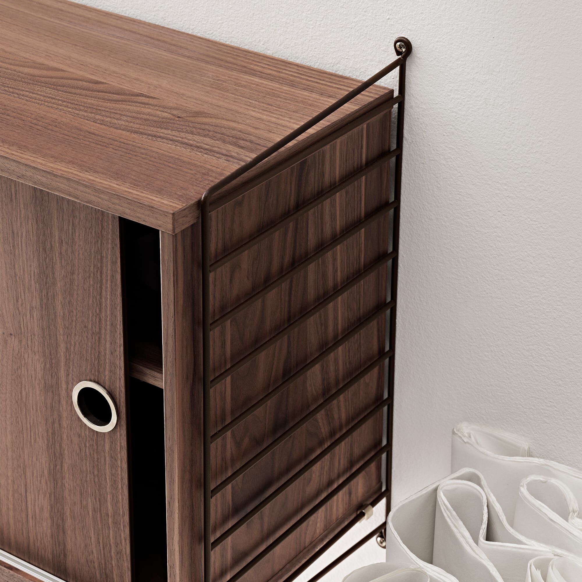 Detalj av skap i valnøtt String veggreol med skapdør.