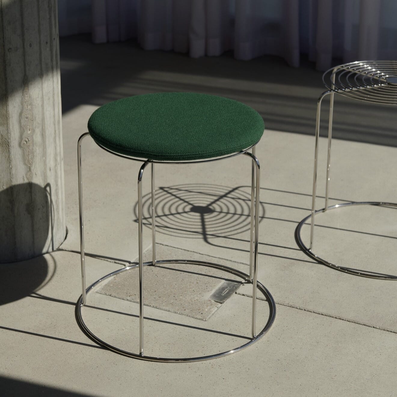 VP11 Wire Stool krakk med grønn sittepute festet med magnet vist mot gulv av beton.