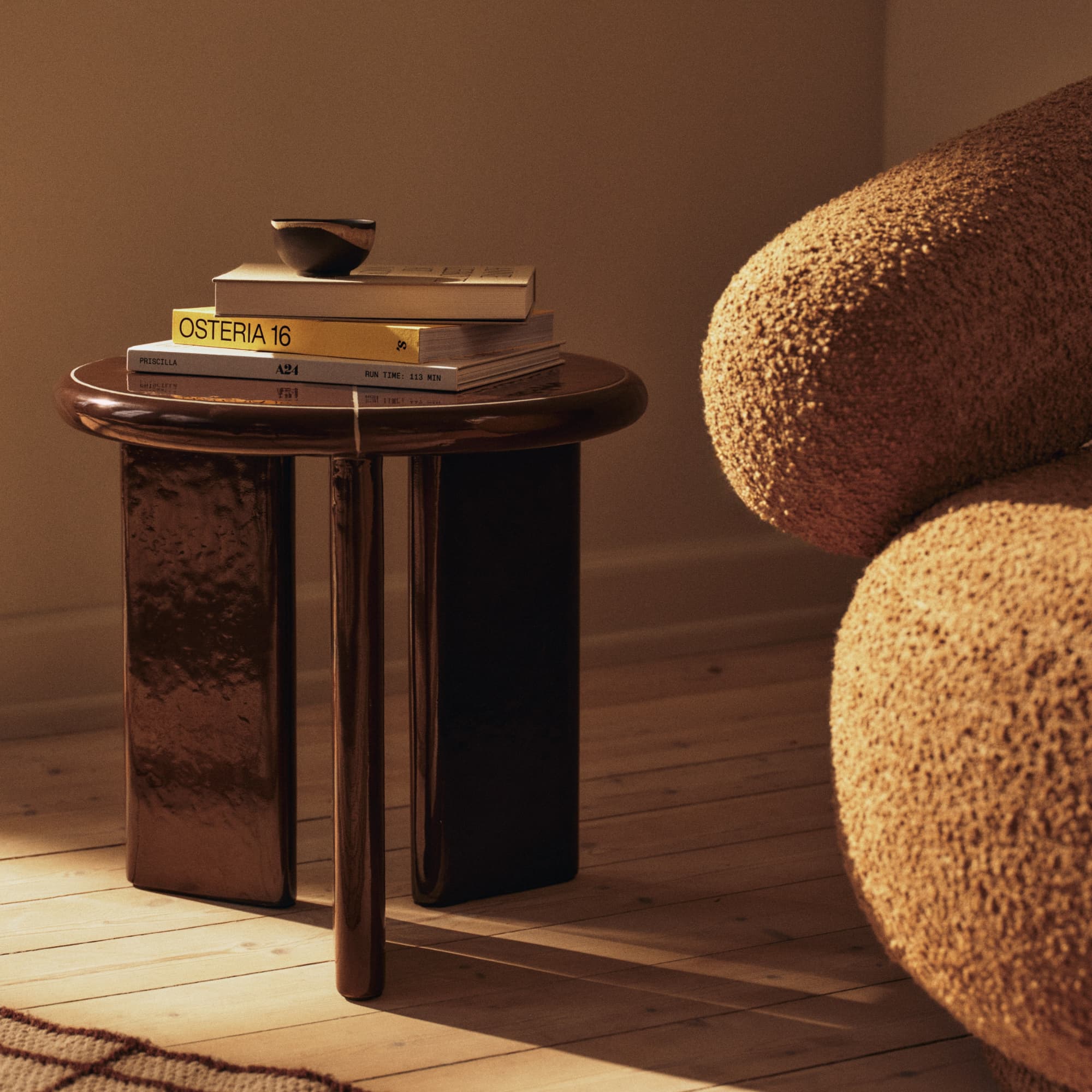 Moderne stue med stein sofabord, brun sofa og hvit loungestol på et lyst, frynset teppe.