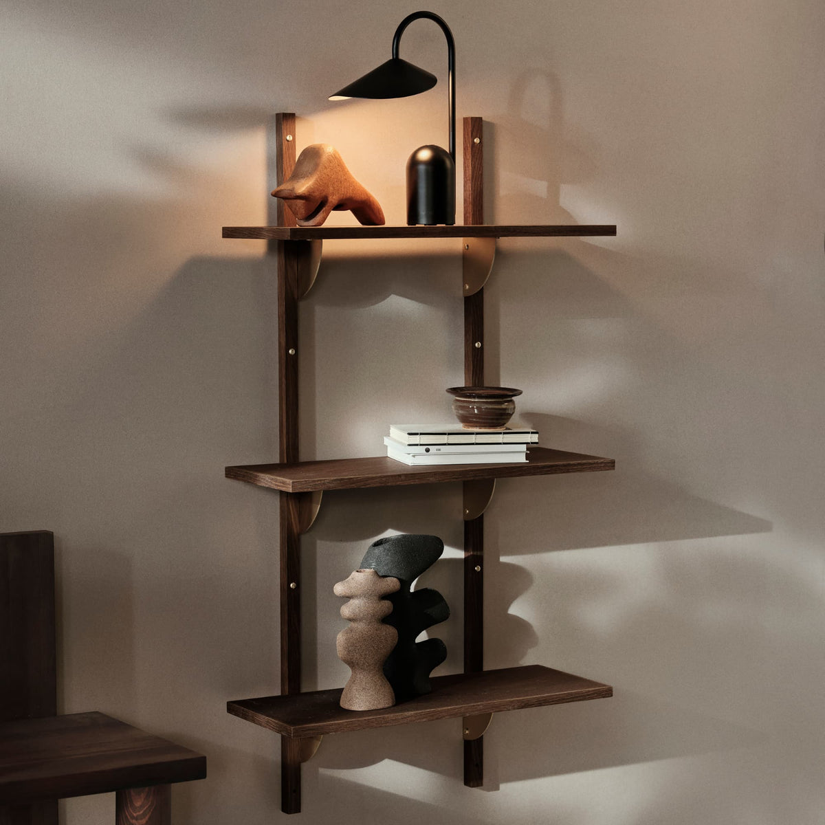 Et lyst, moderne stueområde med beige sofa, trehylle med dekor, glassbord og myke tekstiler i en rolig, skandinavisk stil.