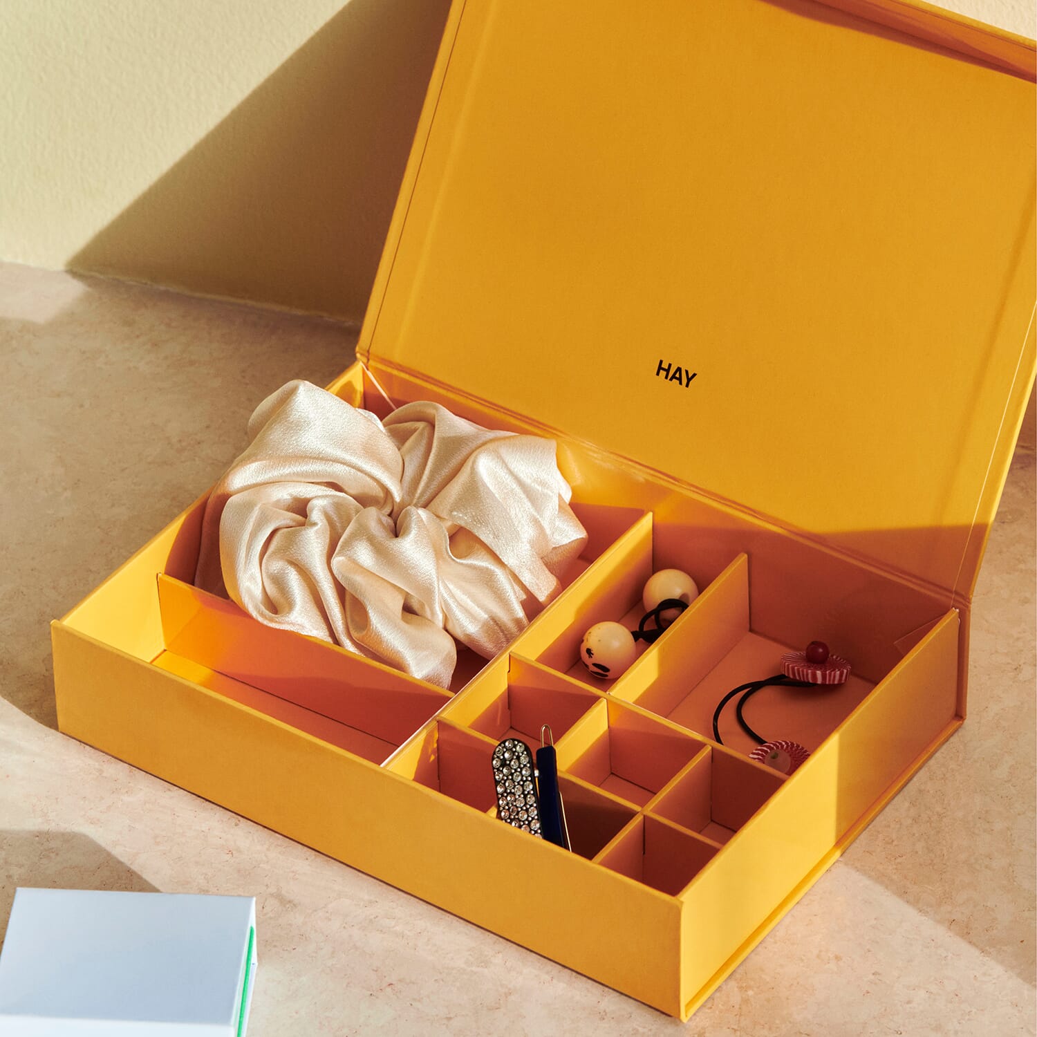 Åpent smykkeskrin i gult med smykker sortert og inndelt i de små rommene i skrinet