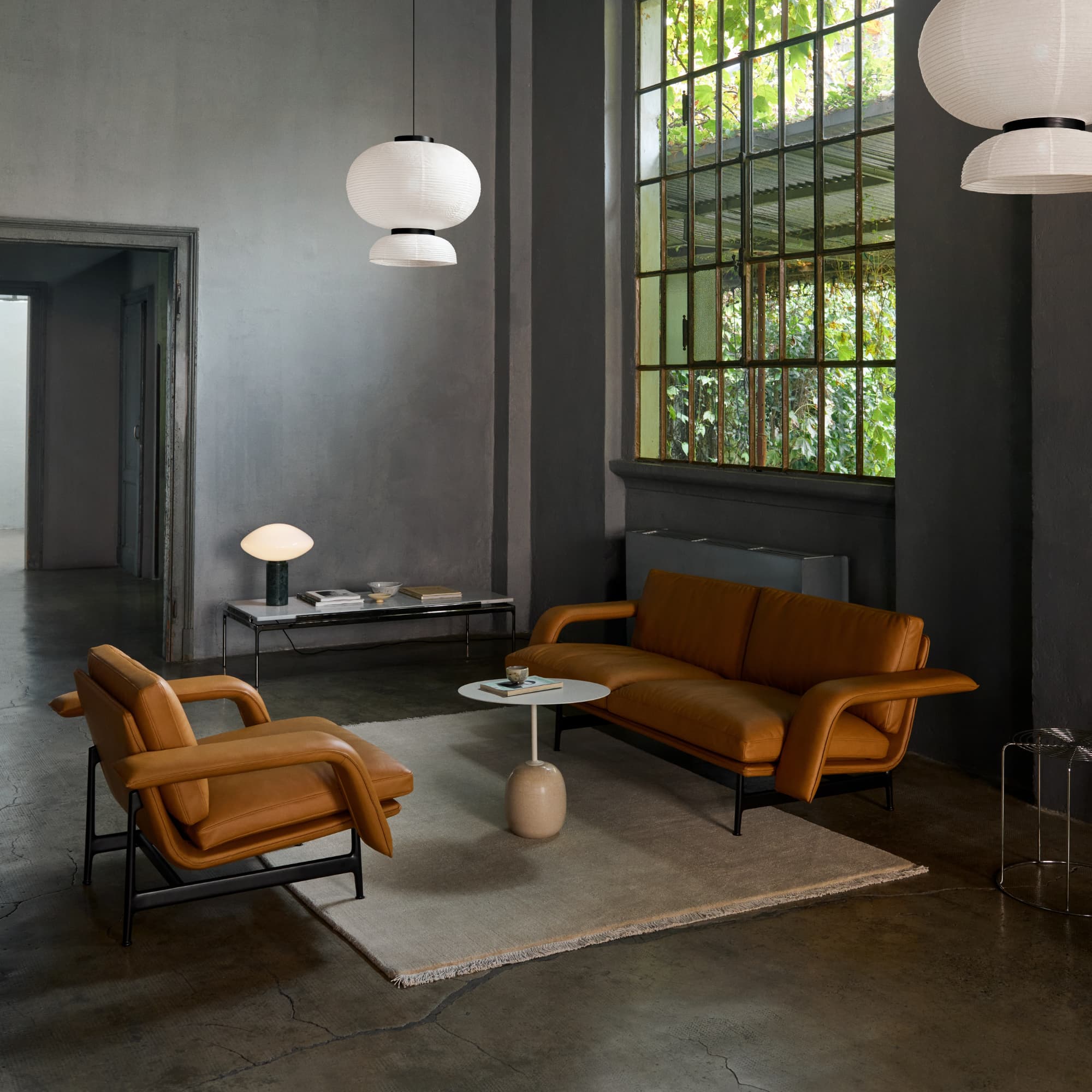 Gulvteppe The Moor i fargen offwhite fra &Tradition, på betonggulv og latto sidebord med marmor fot sammen med skinnsofa i fargen camel. 