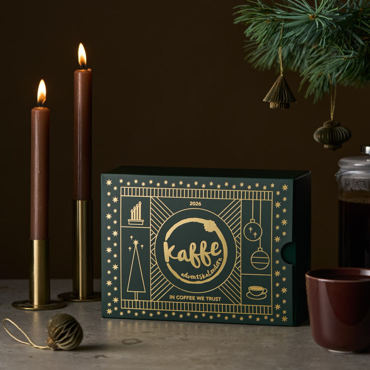 Stemning med kaffekalender og levende lys på et bord sammen med en kaffekopp