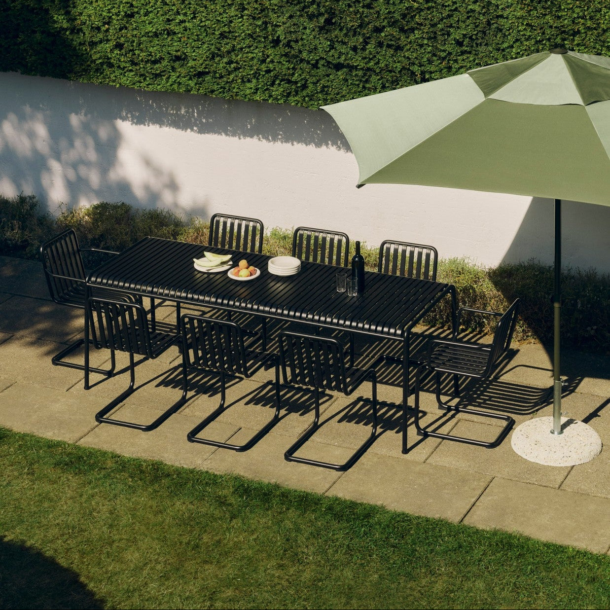 Plissade sort spisestol Cantilever med armlene i svart ved bordenden i en spisegruppe ute