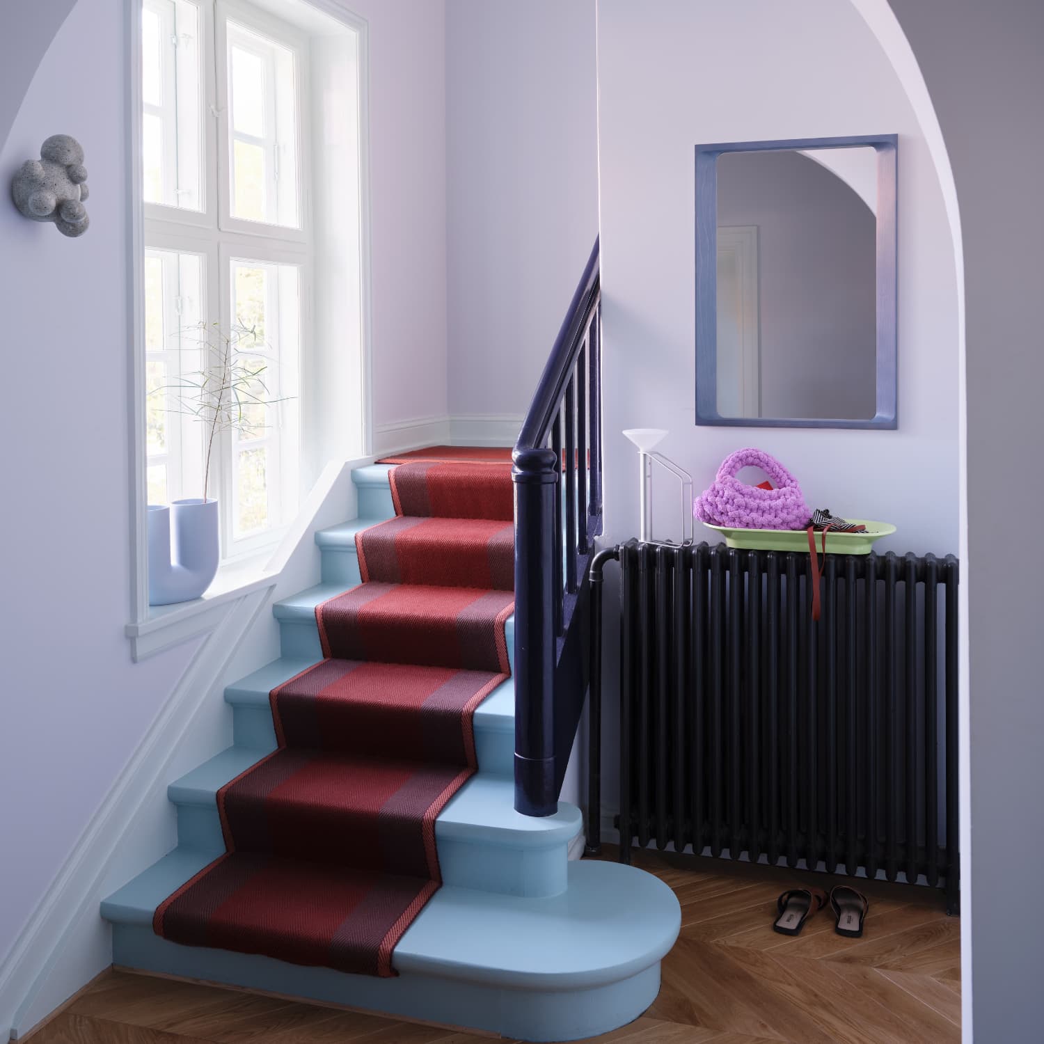 Arced speil 80x55 cm fra Muuto i lys lilla ramme, plassert i gang med trapp og naturlig dagslys