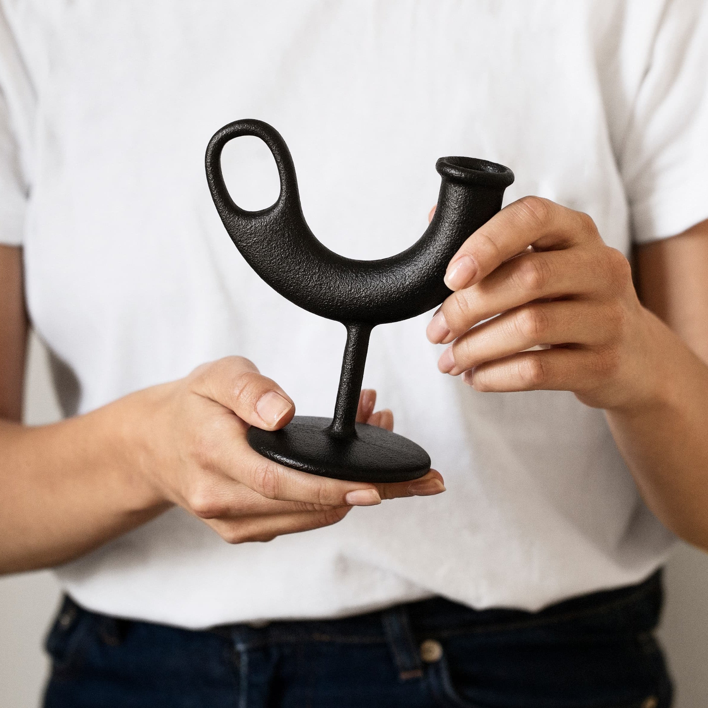 Ildhanen lysestake i støpejern holdt i hånd