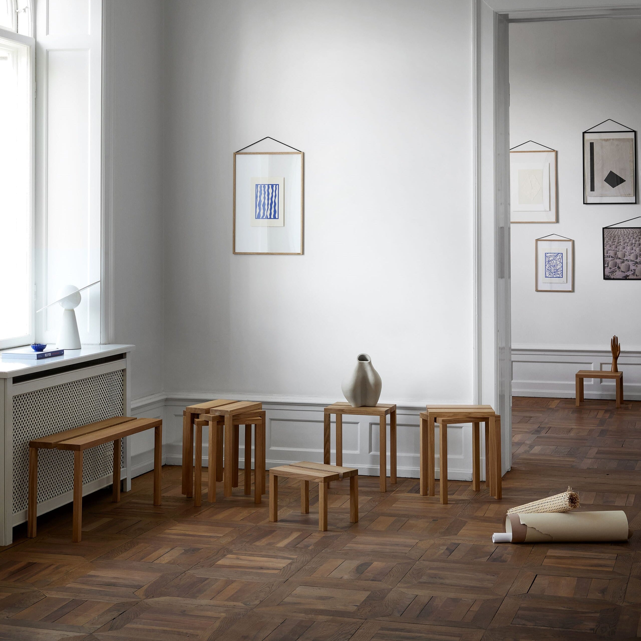 Peg smal benk i eik plassert langs vegg vist med andre krakker i samme serie