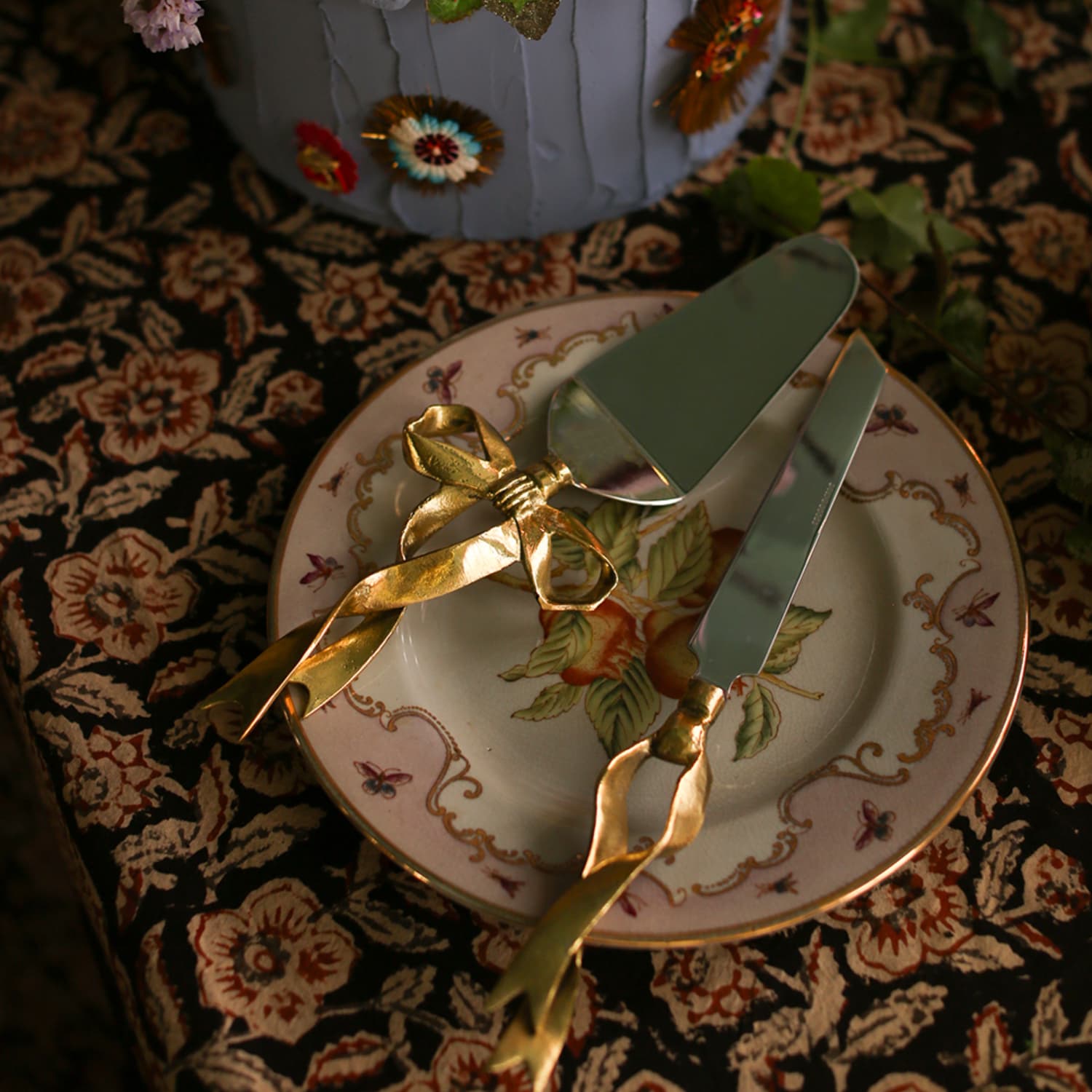 Kakespade og kakekniv med dekorativ sløyfe i resirkulert messing på en tallerken dekket på bordet