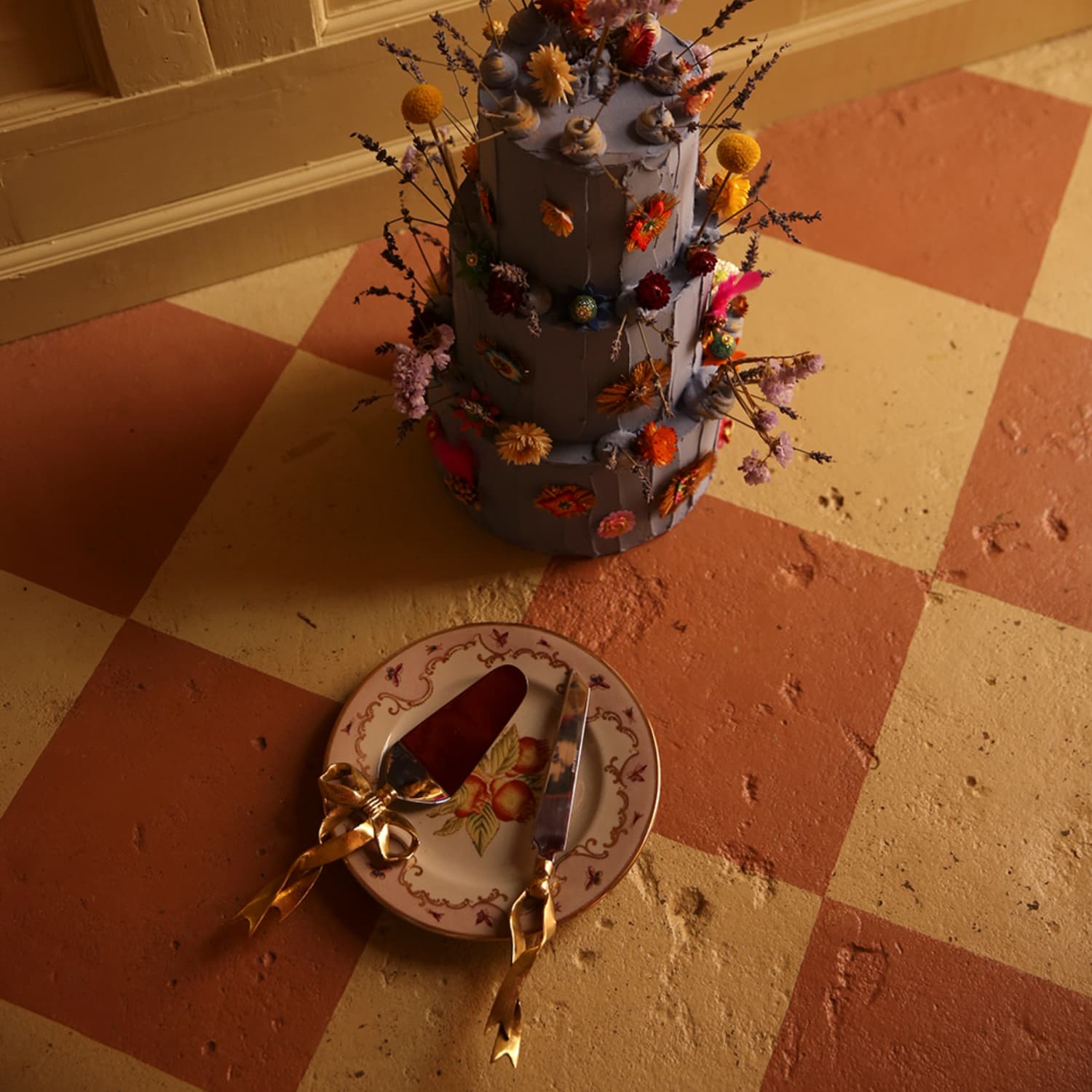 Kakesett med dekorativ sløyfe i resirkulert messing på en tallerken vedsidenav en kake