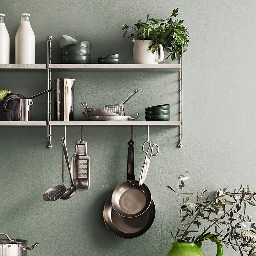 Galvaniserte kroker hengende fra metallhylle med kjøkkenredskaper
