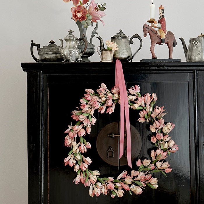 Tulipankrans i malt metall hengt på en skapdør