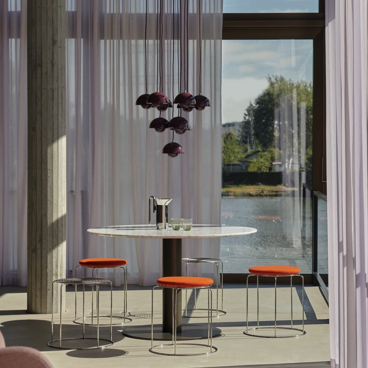 Wire Stool VP11 krakk i speilblankt stål med sitteputer i rødt sammen med spisebord av marmor
